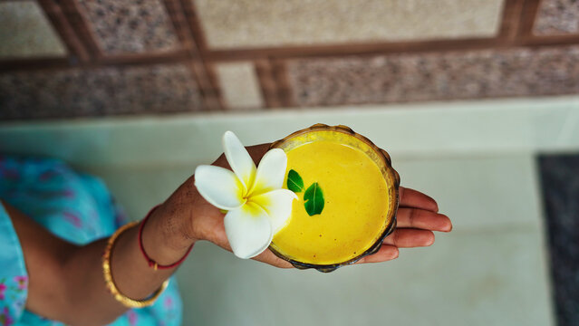 One female hand holding homemade facial in bowl. Ayurvedic face pack of Haldi (Turmeric), Rose water and leaves. mortar of Ubtan for skincare. Natural way for skin beauty using since ancient India