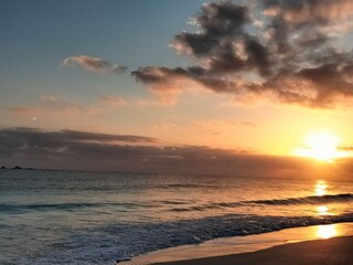 Sun setting behind clouds over North Coast waves