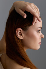 Beauty woman with red hair in profile pose showcasing smooth skin and natural makeup against a...