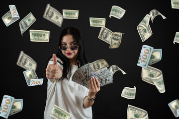 happy prety caucasian woman is standing under dollar rain isolated on black background