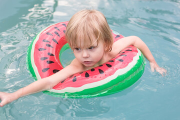 Child in Watermelon-Themed Inflatable Floating in a Pool