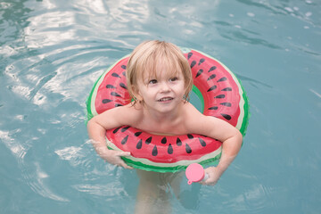 Child in Watermelon-Themed Inflatable Floating in a Pool