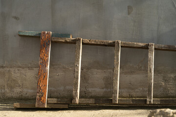 Weathered wooden ladder rests against a textured gray wall, showcasing rustic charm and natural aging, perfect for home decor or construction-themed projects