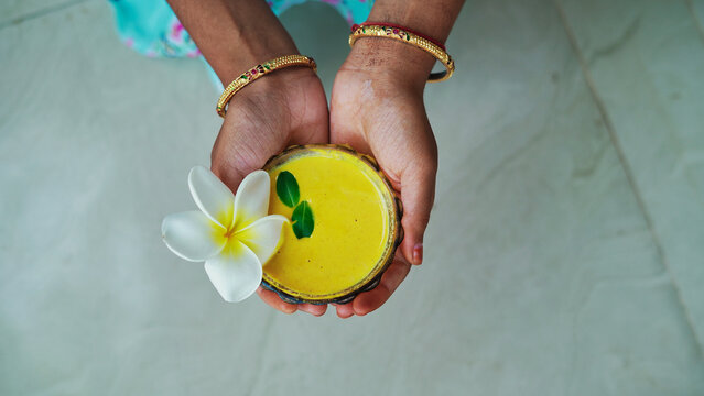 A female hands holding homemade facial in bowl. Ayurvedic face pack of Haldi (Turmeric), Rose water and leaves. mortar of Ubtan for skincare. Natural way for skin beauty using since ancient India