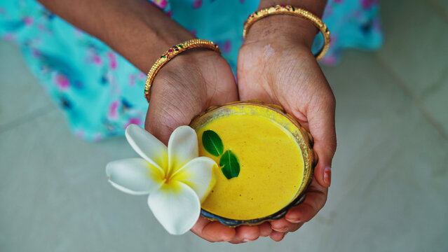 A female hands holding homemade facial in bowl. Ayurvedic face pack of Haldi (Turmeric), Rose water and leaves. mortar of Ubtan for skincare. Natural way for skin beauty using since ancient India