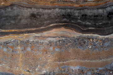 Natural stone surface featuring intricate layers of brown, gray, and black hues, showcasing unique geological patterns and textures, ideal for design and decoration purposes