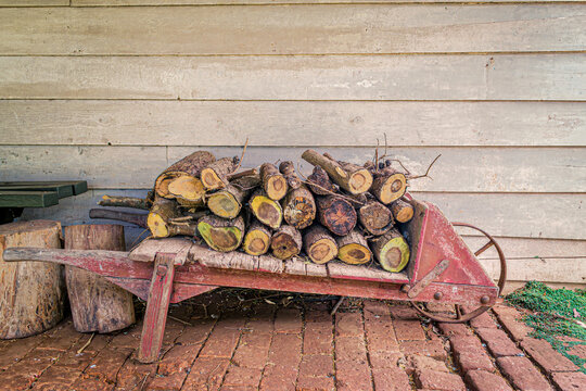 Vintage Wooden Wheelbarrow Holding Chopped Logs Against Wooden Panel Wall