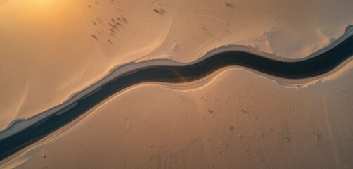 An aerial view of a river bend at sunset that cuts through flat sand