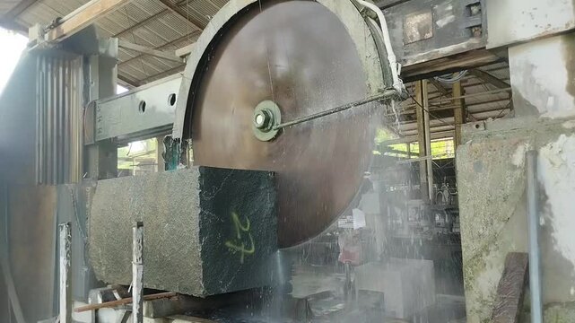 Close-up footage of an industrial granite cutting machine  operating in a construction of fabrication site.