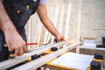 Unrecognizable men measuring wooden plank outdoors