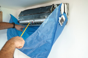 The technician are cleaning the air conditioner by spraying water