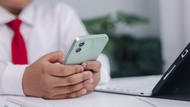Contact us concept with businessman in white shirt and red tie holding smartphone in office. Mobile communication, customer service, and workplace connectivity theme.