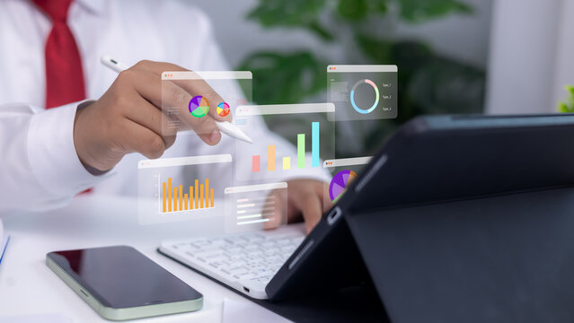 Analytics dashboards and floating holographic charts displayed as a person uses a stylus on a tablet. Concept of modern business analysis, financial planning, and data-driven technology.