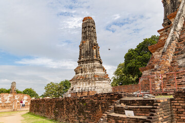 Ancient side prang structure at Wat Chaiwatthanaram in Ayutthaya, Thailand surrounded by red brick...