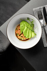 Salmon tartare with avocado and soy sauce dressing on elegant restaurant table