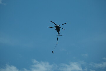 A skydiver leaps out of a flying helicopter high above the clouds, ready for freefall.