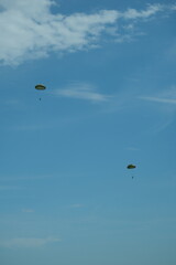 Two parachutists floating gracefully in a clear blue sky during a sunny day.