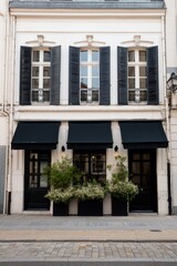 This charming building features elegant black shutters and vibrant floral planters, all set against a peaceful urban backdrop under the daytime sun