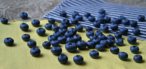 Close-up of blueberries scattered on yellow and striped craft paper.