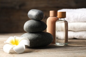 Composition with cosmetic products and spa stones on wooden table, closeup
