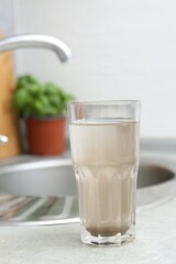 Glass with dirty water near sink indoors