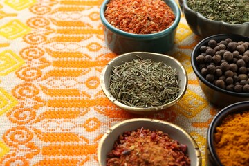 Many different aromatic spices in bowls on table with cloth, closeup. Space for text