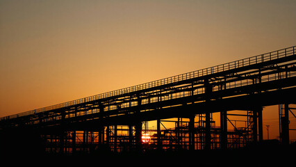 Fototapeta premium Industrial Structure Silhouetted Against a Sunset Sky industry