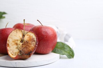 Spoiled apple and good ones on white table, closeup. Space for text