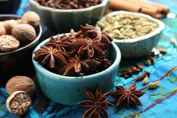 Different aromatic spices on blue tablecloth, closeup