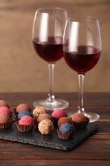 Delicious truffle bonbons and wine on wooden table