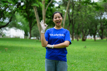 Asian volunteer wearing gloves doing ok sign in a public park