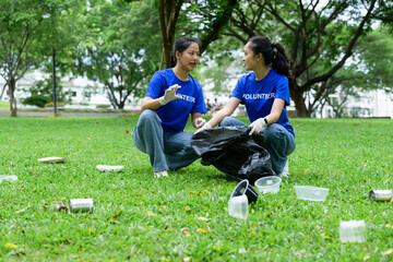 Two volunteers are discussing while collecting trash in a park