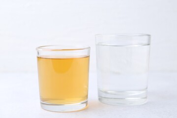 Glasses with clean and dirty water on light table, closeup