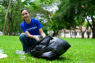 Young volunteer picking up trash in park wearing gloves and blue t-shirt