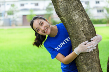 Young volunteer hugging a tree wearing gloves and smiling in a park