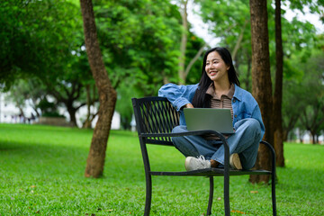 Young student using laptop while sitting on bench in park