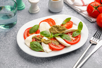 Tasty salad Caprese served with pesto sauce on grey table, closeup