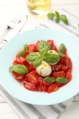 Tasty salad Caprese with mozzarella, tomatoes, basil and spices on white wooden table, closeup