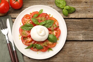 Tasty salad Caprese served with pesto sauce on wooden table, flat lay. Space for text