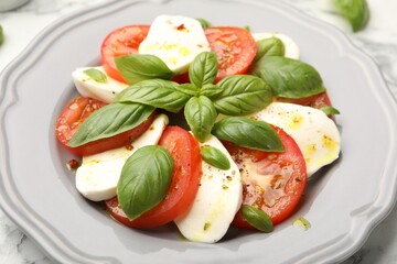 Tasty salad Caprese with mozzarella, tomatoes, basil and spices on table, closeup