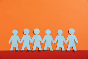 Human paper figures holding hands on color background, flat lay. Space for text