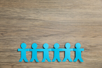 Human paper figures holding hands on wooden background, flat lay