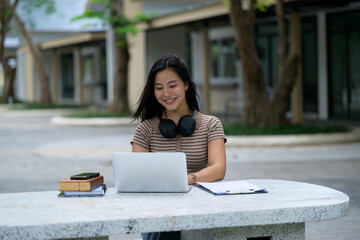 Happy student working on her laptop on campus, embracing technology for learning