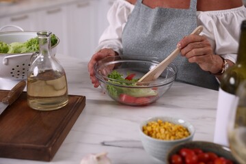 Senior woman cooking at marble table indoors, closeup