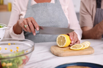 Elderly couple cooking together at white marble table indoors, closeup