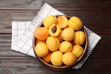 Fresh apricots in bowl on wooden table, top view