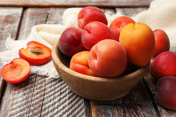 Fresh ripe apricots in bowl on wooden table, closeup