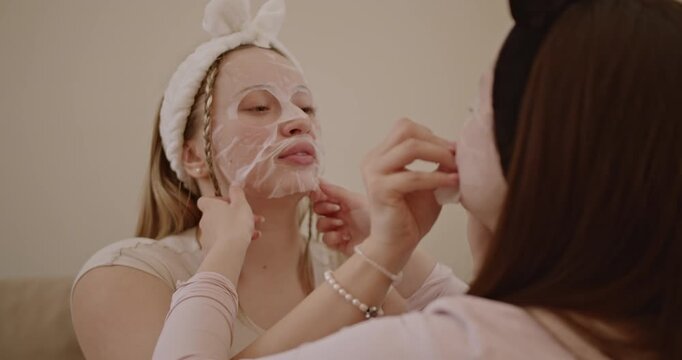 Two young women enjoy a relaxing spa day at home, applying face masks and spending quality time together. - Powered by Adobe