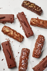 Delicious chocolate bars covered in nuts and chocolate shavings resting on white background
