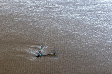 Abandoned scooter half-submerged in tidal mud